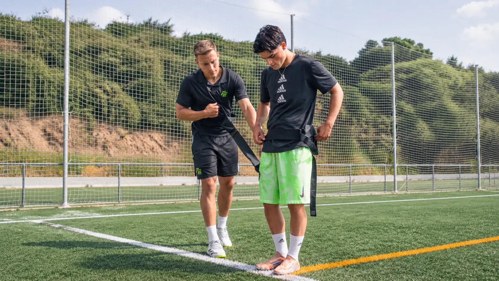 Entrenador de Focus Elite ajustando la cinta de resistencia a un jugador en el campo