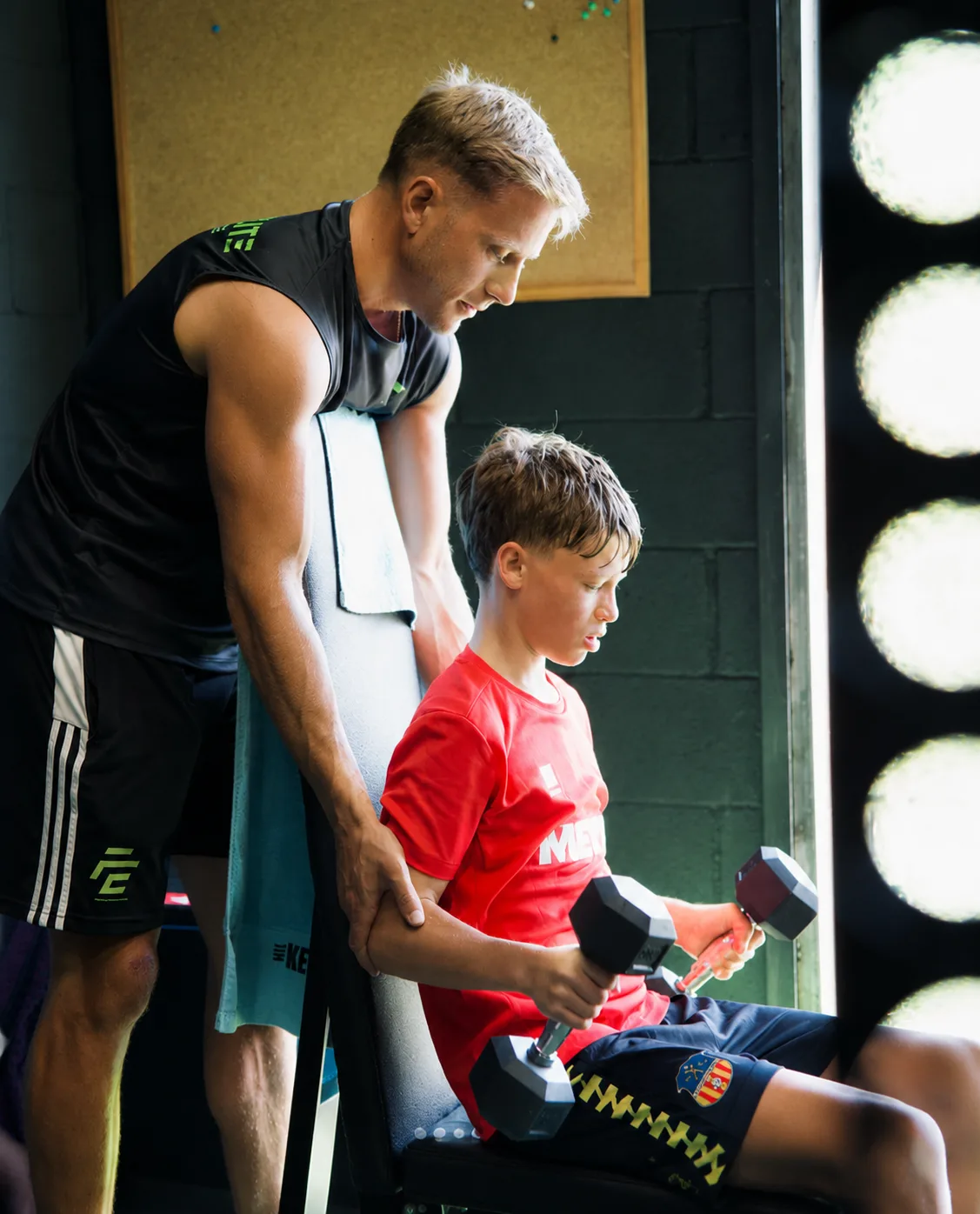 Entrenador de Focus Elite guiando a un chico que entrena con mancuernas